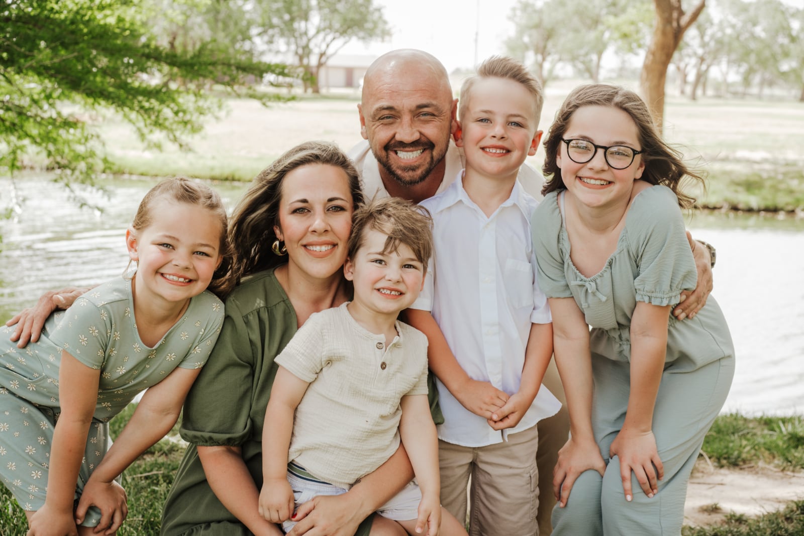 The Neudorf family, owners of Titan Steel Buildings, smiling together in an outdoor family portrait.