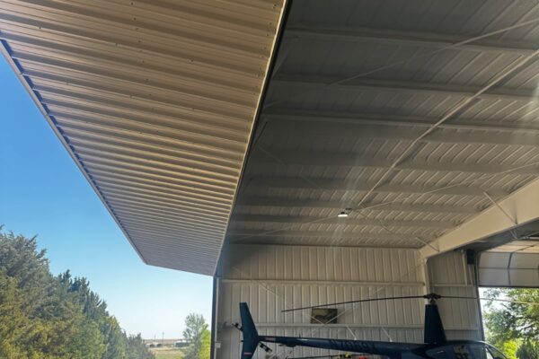 Wide open metal hangar door with a private helicopter inside, built by Titan Steel Buildings.